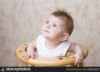 Baby boy sitting on high chair, looking up