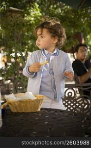 Baby boy standing on a chair with a French fry in his hand, Santo Domingo, Dominican Republic