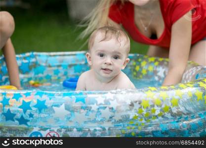 Baby boy swimming in inflatable pool at garden with mother