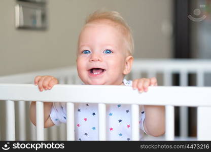 Baby boy with blue eyes standing in crib