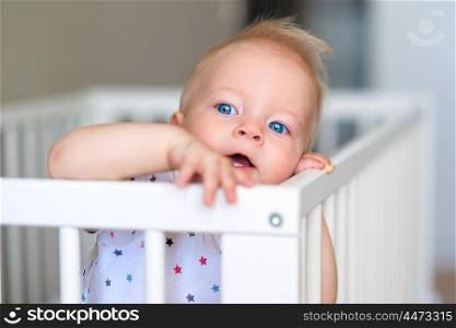 Baby boy with blue eyes standing in crib