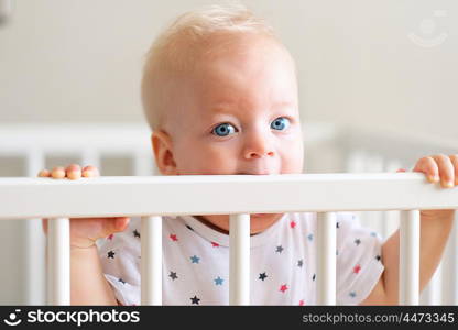 Baby boy with blue eyes standing in crib