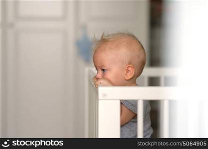 Baby boy with blue eyes standing in crib