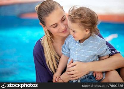 Baby boy with mom on the beach resort, happy family having fun near the pool, enjoying summer vacation and time with each other 