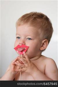 Baby boy with paper lips on a stick shows tongue