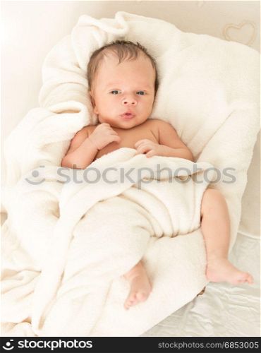 Baby boy with soother lying in wicker basket
