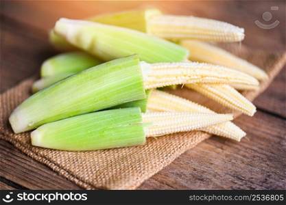 Baby corn on the sack, Fresh young baby corn for cooking health food, Close up raw organic baby corn on wooden background.