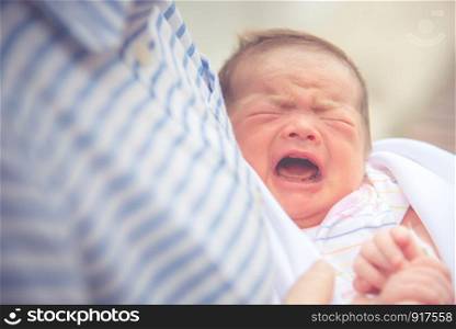 Baby crying in mother embrace. Newborn and infant healthy concept. Birthday and love of mother theme.