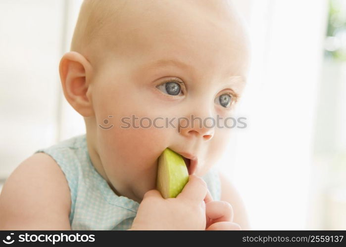 Baby eating apple indoors