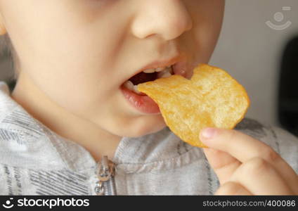 Baby eating chips. Close-up. The child holds the chips. Junk food.. Baby eating chips. Close-up. The child holds the chips.