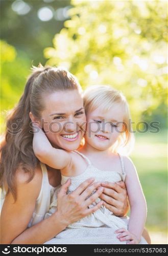 Baby embracing mother outdoors
