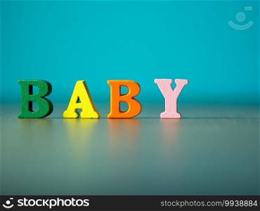 Baby. English alphabet made of wooden letter color. Alphabet baby on wooden table and background is powder blue.