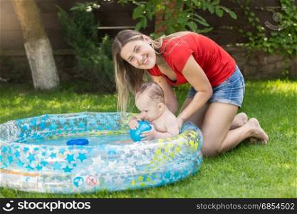 Baby enjoying swimming in the pool at garden with young mother