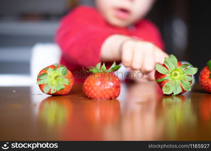 Baby exploring some fruits with his hand on a dark wooden table. Baby s hand manipulating different fruits on a wooden table