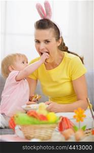Baby feeding mother with Easter cookie
