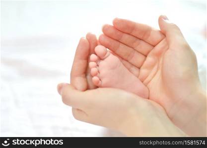 Baby feet in mother hands. Mom and her Child. Happy Family concept. Beautiful conceptual image of Maternity. Baby feet in mother hands.