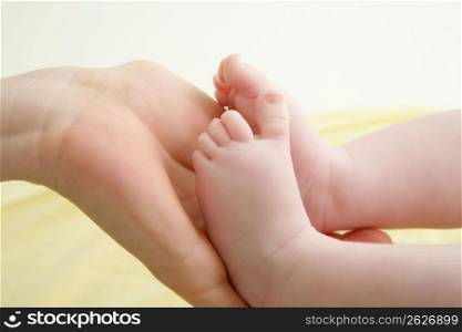 baby feet in mother hands playing together