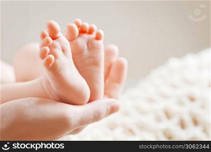 Baby feet in mother hands. Tiny Newborn Baby&rsquo;s feet on female Shaped hands closeup. Mom and her Child. Happy Family concept. Beautiful conceptual image of Maternity