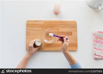 baby food and nutrition concept - mother hands with jar, spoon and bowl preparing cereal from powder. hands with spoon and jar making baby cereal