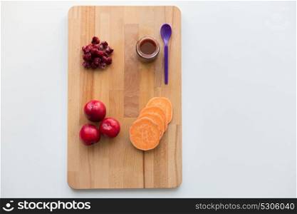 baby food, healthy eating and nutrition concept - fruit puree in glass jar with feeding spoon on wooden board. fruit puree or baby food in jar and feeding spoon