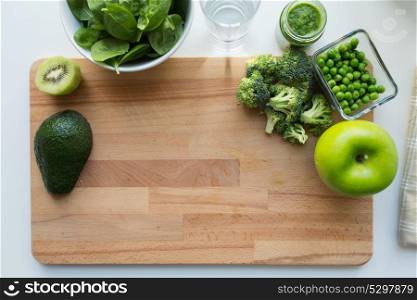 baby food, healthy eating and nutrition concept - glass jar of green vegetable puree and fruits on wooden board with copy space. vegetable puree or baby food and fruits on board
