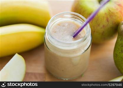 baby food, healthy eating and nutrition concept - glass jar with apple, pear and banana fruit puree on wooden board. jar with fruit puree or baby food