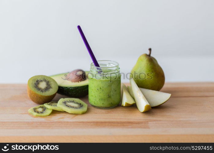 baby food, healthy eating and nutrition concept - glass jar with green fruit puree on wooden cutting board. jar with fruit puree or baby food on wooden board