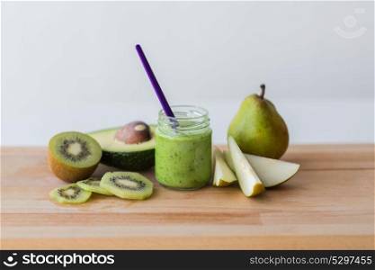 baby food, healthy eating and nutrition concept - glass jar with green fruit puree on wooden cutting board. jar with fruit puree or baby food on wooden board