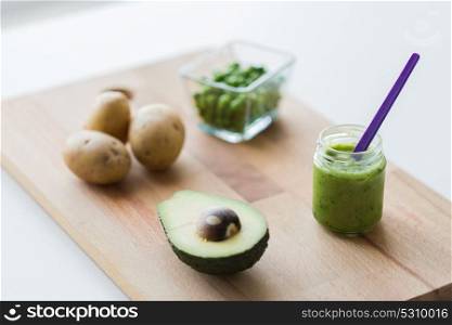 baby food, healthy eating and nutrition concept - glass jar with green vegetable puree on wooden cutting board. jar with puree or baby food on wooden board