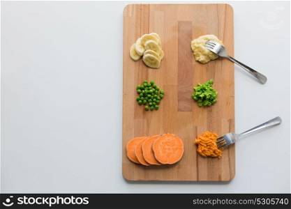 baby food, healthy eating and nutrition concept - mashed fruits and vegetables with forks on wooden cutting board. mashed fruits and vegetables with forks on board