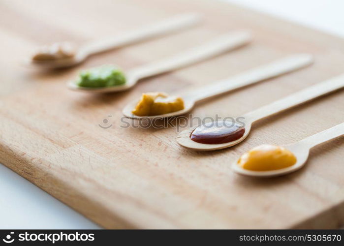 baby food, healthy eating and nutrition concept - vegetable or fruit puree in wooden spoons. vegetable or fruit puree or baby food in spoons