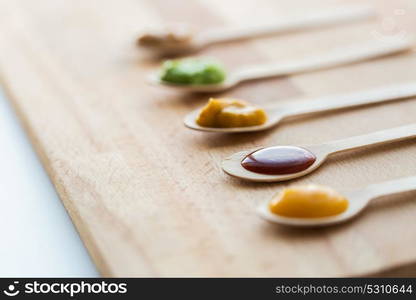 baby food, healthy eating and nutrition concept - vegetable or fruit puree in wooden spoons. vegetable or fruit puree or baby food in spoons