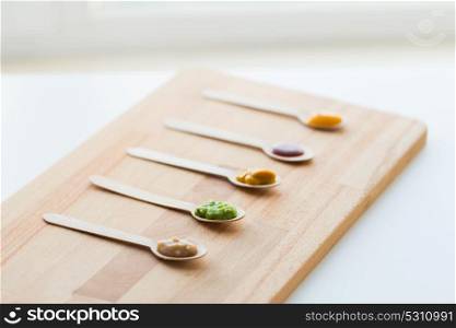 baby food, healthy eating and nutrition concept - vegetable or fruit puree in wooden spoons. vegetable or fruit puree or baby food in spoons