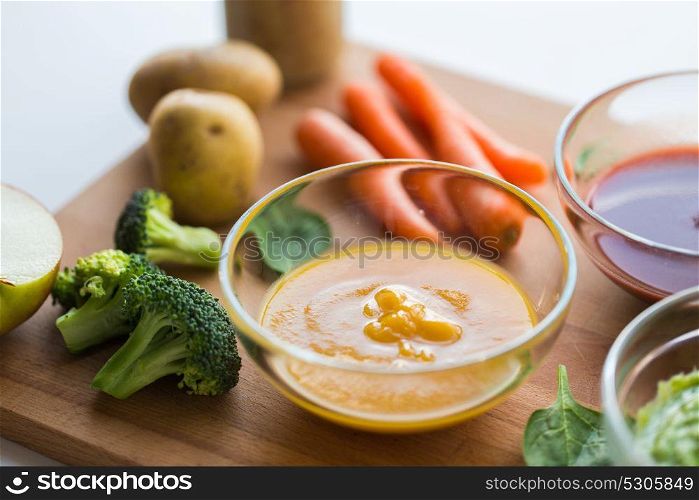 baby food, healthy eating and nutrition concept - vegetable puree in glass bowl on wooden board. vegetable puree or baby food in glass bowl