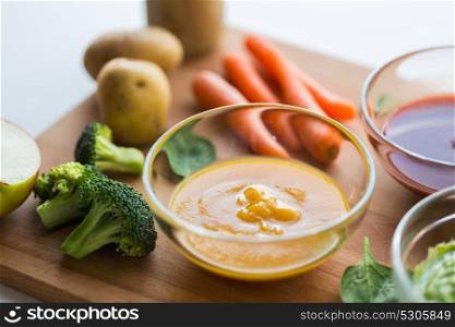 baby food, healthy eating and nutrition concept - vegetable puree in glass bowl on wooden board. vegetable puree or baby food in glass bowl