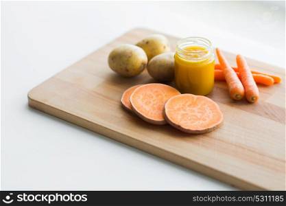 baby food, healthy eating and nutrition concept - vegetable puree in glass jar on wooden board. vegetable puree or baby food in glass jar