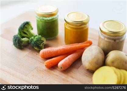 baby food, healthy eating and nutrition concept - vegetable puree in glass jars on wooden board. vegetable puree or baby food in glass jars