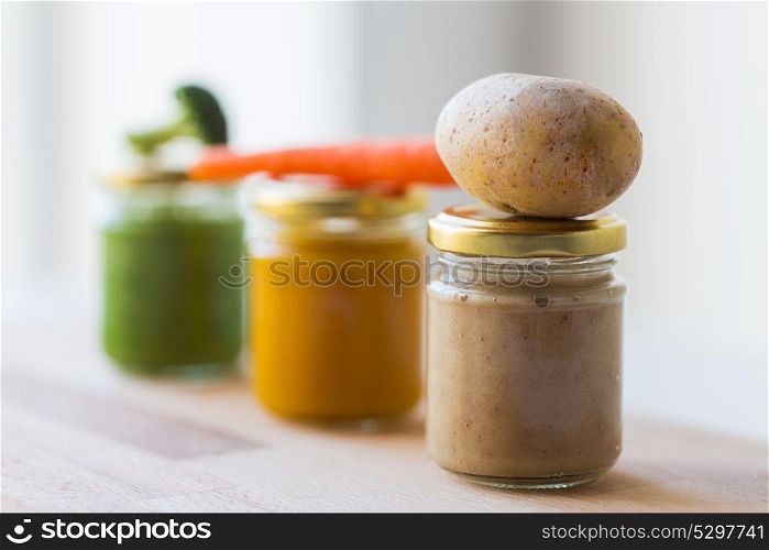 baby food, healthy eating and nutrition concept - vegetable puree in glass jars on wooden board. vegetable puree or baby food in glass jars