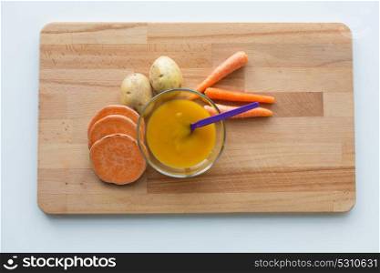 baby food, healthy eating and nutrition concept - vegetable puree or baby food in bowl with feeding spoon on wooden board. vegetable puree or baby food in bowl with spoon