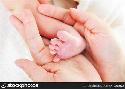 baby foot in mother hand closeup