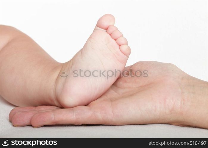 Baby foot in mother hands on white background