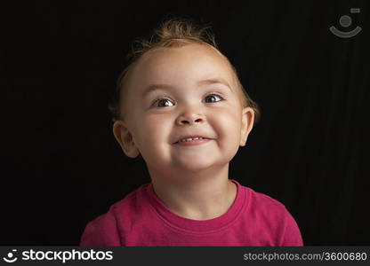 Baby girl (1-2) on black background close-up