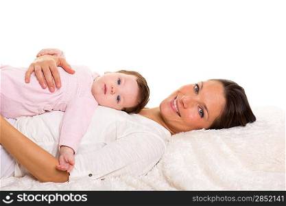 Baby girl and mother lying happy together on white fur blanket