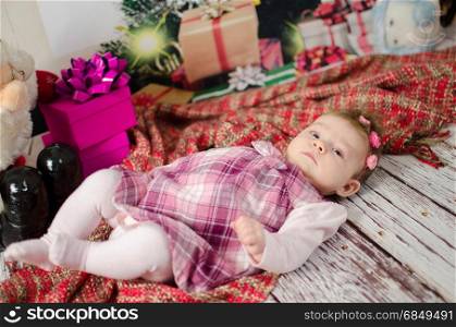 baby girl enjoying her first Christmas with lots of gifts under Christmas tree