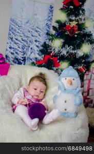 baby girl enjoying her first Christmas with lots of gifts under Christmas tree