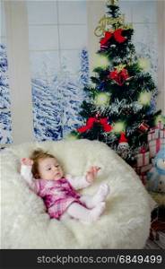 baby girl enjoying her first Christmas with lots of gifts under Christmas tree