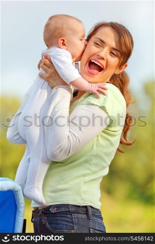 Baby girl kissing holding her happy mother&#xA;