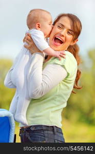 Baby girl kissing holding her happy mother&#xA;