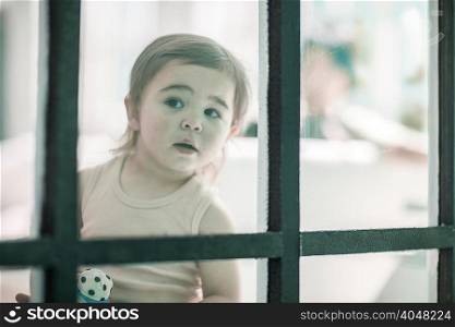 Baby girl looking through window