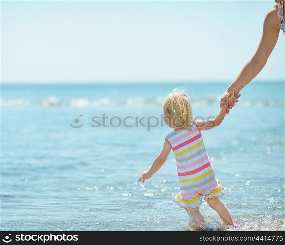 Baby girl pulling mother in sea